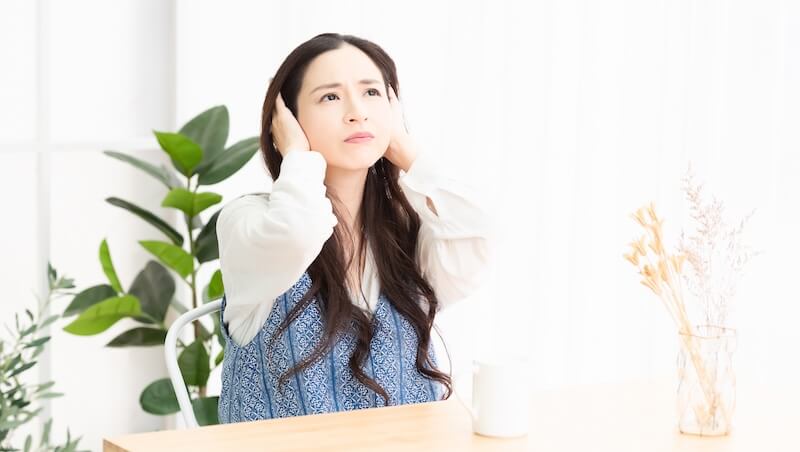 騒音に困って耳を塞いでいる主婦